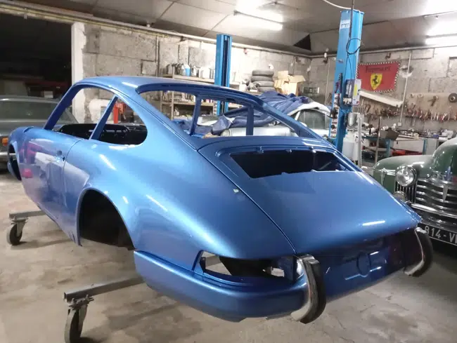 Porsche 911 bleue, vue trois-quarts en atelier